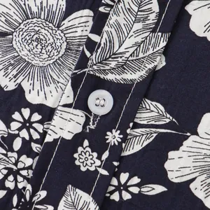 Dettaglio ravvicinato del tessuto di una camicia floreale blu scuro con bottone bianco
