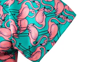 Detailed close-up view of shirt sleeve featuring pink flamingo prints on turquoise fabric