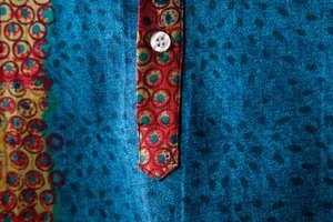 Detailed macro shot of ethnic floral print and white button on men's blue linen casual shirt