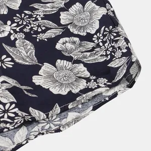 Dettaglio della stampa floreale bianca e della trama del tessuto della camicia blu