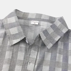 Dettaglio del colletto di una camicia a quadri grigia da uomo con etichetta taglia M