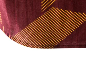 Close-up detail of the hem and geometric striped pattern on a burgundy linen shirt.