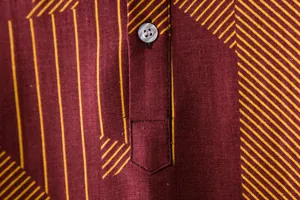 Close-up of men's burgundy linen shirt featuring a yellow geometric pattern and button detail