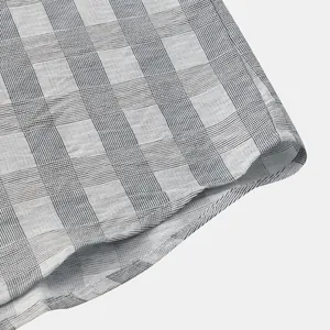 Dettaglio di una camicia da uomo a maniche corte con un classico motivo a quadri grigio e bianco.