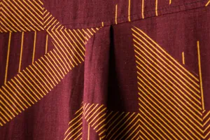Close-up detail of maroon cotton linen shirt with yellow geometric striped pattern