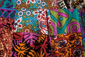 Makro-Detailansicht der lebendigen floralen und Paisley-Patchwork-Stoffstruktur am Hemd