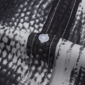 Close-up of snake skin print fabric with a white button and stitching detail
