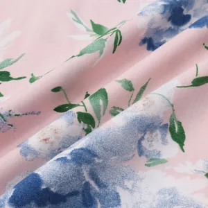 Makroaufnahme von rosa Hawaiihemdenstoff mit blauem Blumendruck und grünen Blättern.