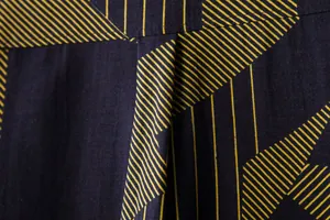 Macro detail of a navy blue casual linen shirt with yellow geometric pinstripe pattern