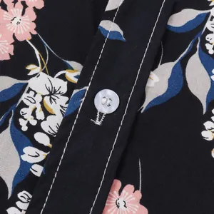 Nahaufnahme des floralen Hawaiihemd-Stoffs mit Knopf und weißen Steppnaht-Details