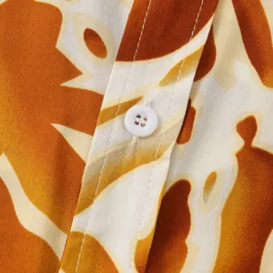 Close-up detail of men's floral shirt fabric showing white button and ochre print pattern