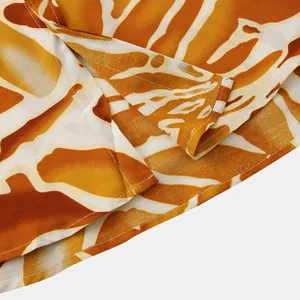 Macro detail of the hem and precise stitching on a men's vibrant orange floral print shirt.