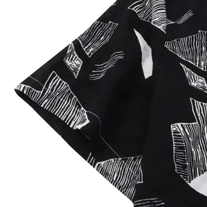 Close-up detail of men's Hawaiian shirt with white abstract geometric pattern on black fabric