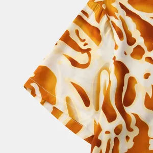 Close-up detail of the vibrant abstract orange floral print on a men's summer short sleeve shirt