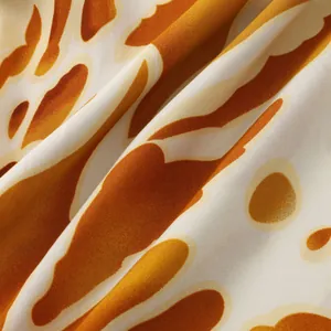 Close-up detail of soft fabric with vibrant abstract orange and cream floral print