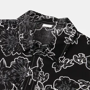 Close-up detail of a men's black short sleeve shirt with white floral line-art pattern.