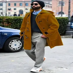 Vista de estilo callejero de un abrigo trenca grueso amarillo mostaza con botones de cuerno.