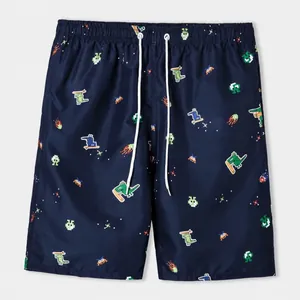 Macro view of navy blue swim trunks featuring fun pixel art dinosaur surfing pattern.