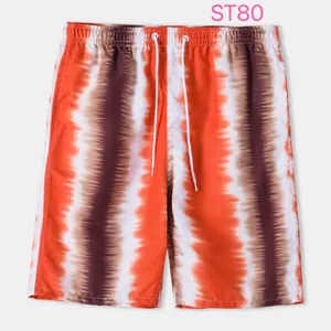 Detail view of men's beach shorts with orange and brown tie-dye vertical stripes.
