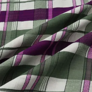 Detailed macro shot of green and purple plaid woven cotton fabric for casual beach shirts