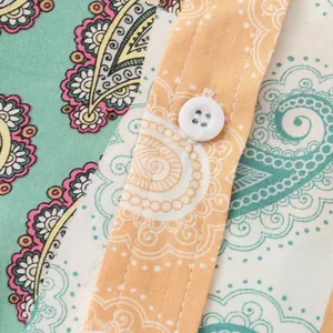 Detailed view of the paisley printed fabric and white button on this men's floral shirt