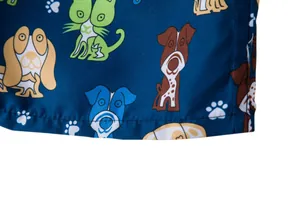 Close-up of men's beach shorts fabric featuring vibrant cartoon dog prints and stitching