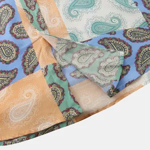 Close-up of the curved hem and stitching on a colorful paisley patchwork men's shirt.