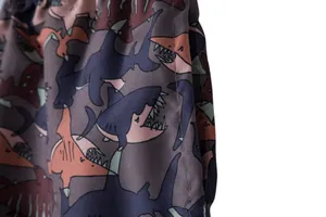 Close-up of men's beach shorts with colorful cartoon shark print and side pocket detail