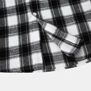 Close-up of black and white plaid shirt hem with white button and fabric texture