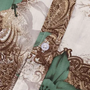 Close-up detail of a men's shirt featuring a brown and green paisley pattern and white button.