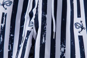 Close-up of navy blue and white striped beach shorts with anchor pattern and drawstring.
