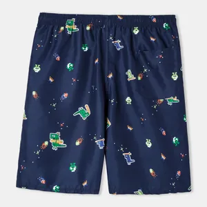 Close-up view of navy blue swimming trunks featuring pixel dinosaur and meteorite prints