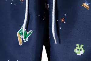 Detailed close-up of pixelated monster patterns and drawstring on navy blue beach shorts