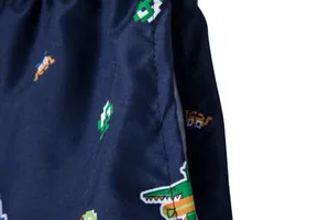 Close-up of pixelated crocodile pattern on navy blue quick-dry beach shorts