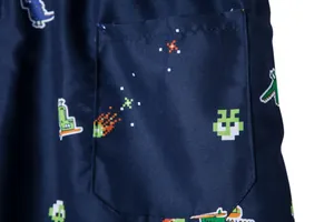 Macro detail of navy blue beach shorts showing pixel art dinosaur print and pocket sewing