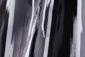 Close-up of men's beach shorts showing white drawstring and black brushstroke pattern