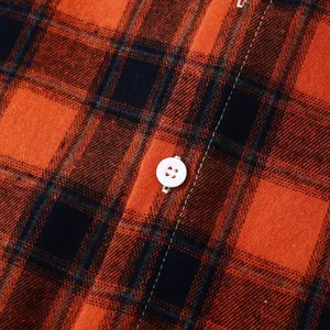 Detailed macro shot of red and black plaid flannel shirt texture with white button