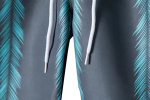 Detailed macro view of white drawstring and teal palm leaf print on men's beach shorts.