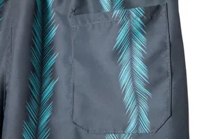 Close-up detail of men's swim trunks featuring a side pocket and teal leaf pattern