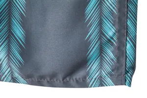 Macro detail showing teal palm leaf pattern and quality stitching on men's beach shorts