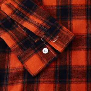 High-quality close-up detail of orange and black plaid shirt sleeve cuff and white button