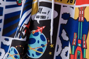 Close-up detail of comic print fabric and white drawstring on men's beach shorts.