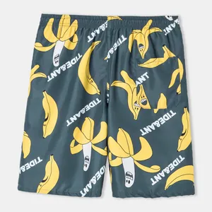 Close-up of men's beach shorts with funny cartoon banana pattern and pocket detail.