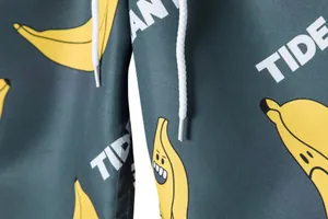 Close-up detail of men's beach shorts fabric featuring a quirky banana pattern and drawstring.