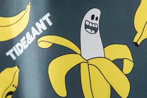 Macro detail of men's swim trunks with creative cartoon banana and ghost pattern print.
