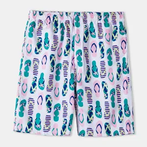 Close-up view of men's white beach shorts featuring a vibrant flip-flop print design