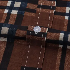 Close-up macro view of brown plaid fabric texture and button detail on a casual shirt.