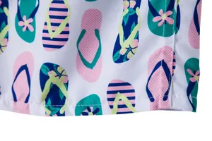 Macro detail of men's beach shorts featuring a vibrant colorful flip-flop pattern print