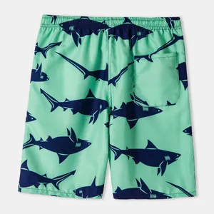 Detail of mint green men's swim trunks featuring dark blue shark print