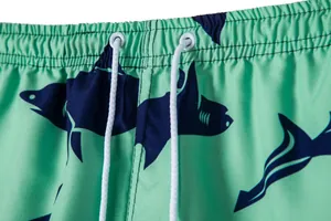 Close-up of men's beach shorts featuring shark print and drawstring waistband detail